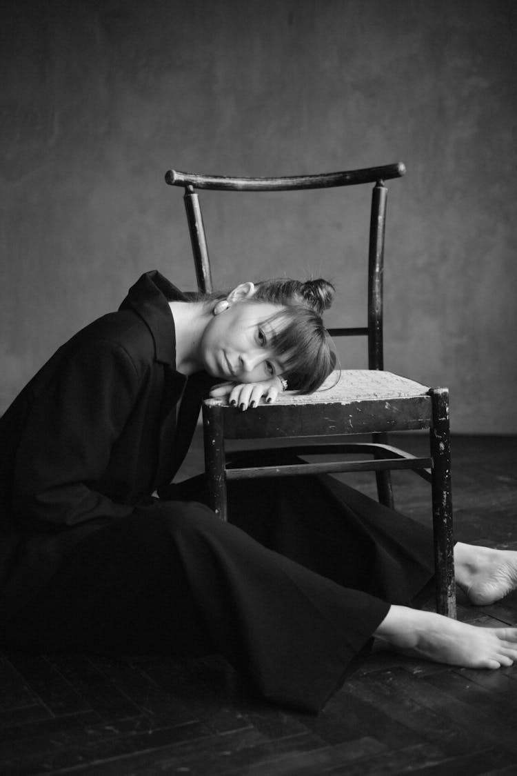 Barefoot Woman In Black Leaning Head On Chair