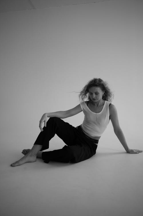 Black and White Studio Shot of a Woman Wearing a White Top and Black Trousers 