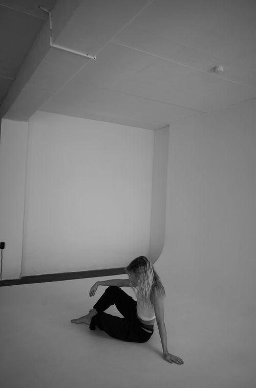 Free Black and white minimalist studio photo of a woman sitting on the floor, enhancing simplicity and elegance. Stock Photo