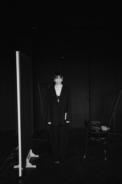 Free Black and white photo of a woman in a modern suit standing in a minimalist studio setting. Stock Photo