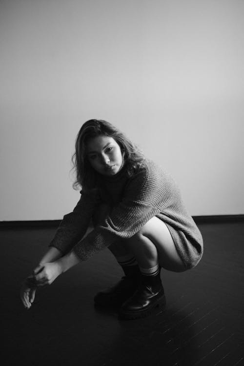 Black and White Studio Shot of a Young Woman Wearing Boots and Sweater 