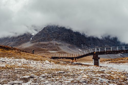 Free Breathtaking mountain landscape in Gjevilvasshytta, Norway with cloudy skies and a rustic bridge. Stock Photo