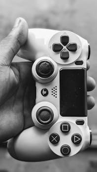 Black and white image of a hand holding a gaming controller, highlighting technology and grip.
