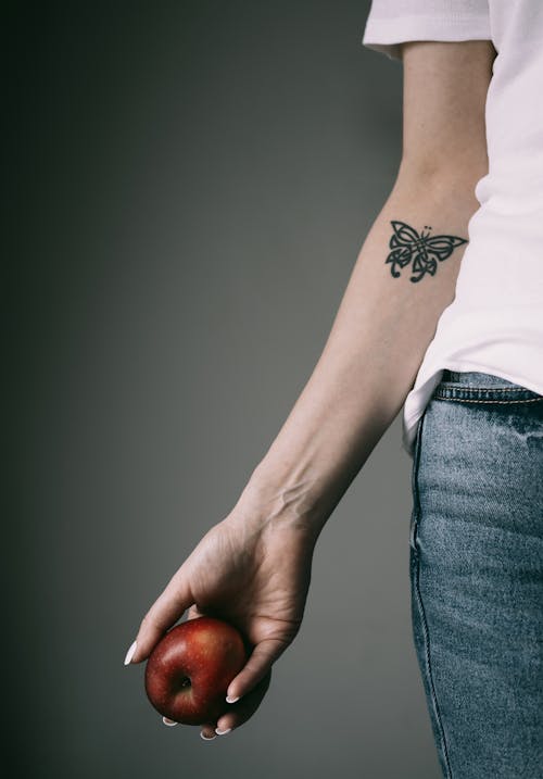 Woman Arm with Tattoo Holding Apple