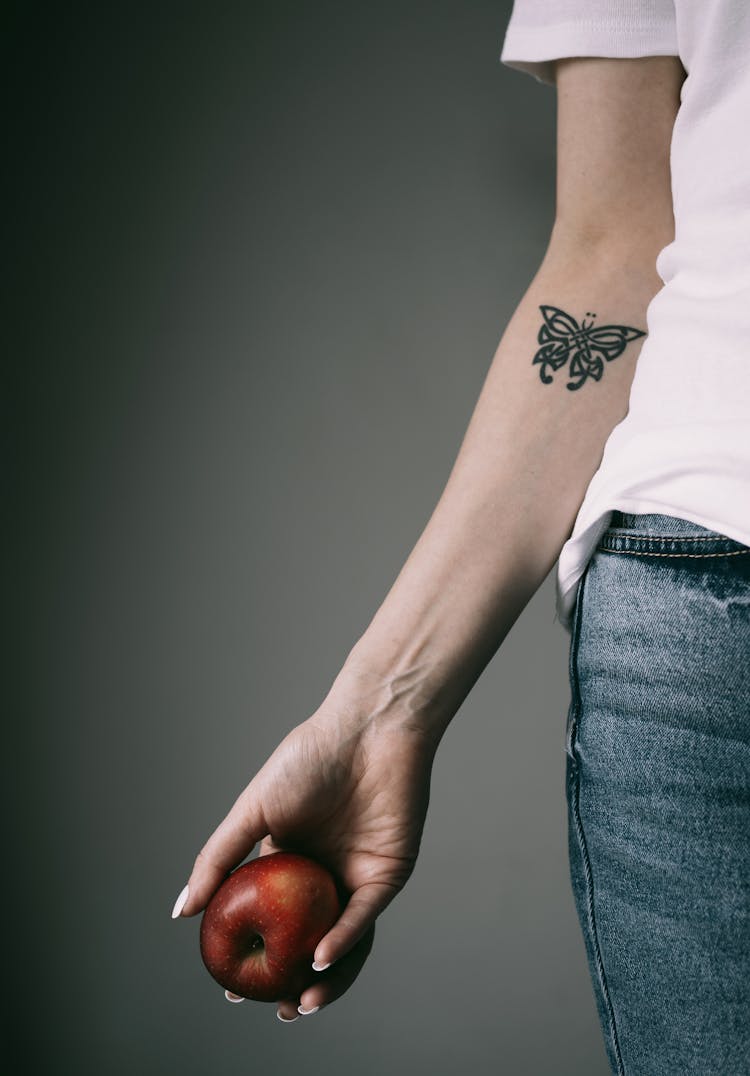 Woman Arm With Tattoo Holding Apple