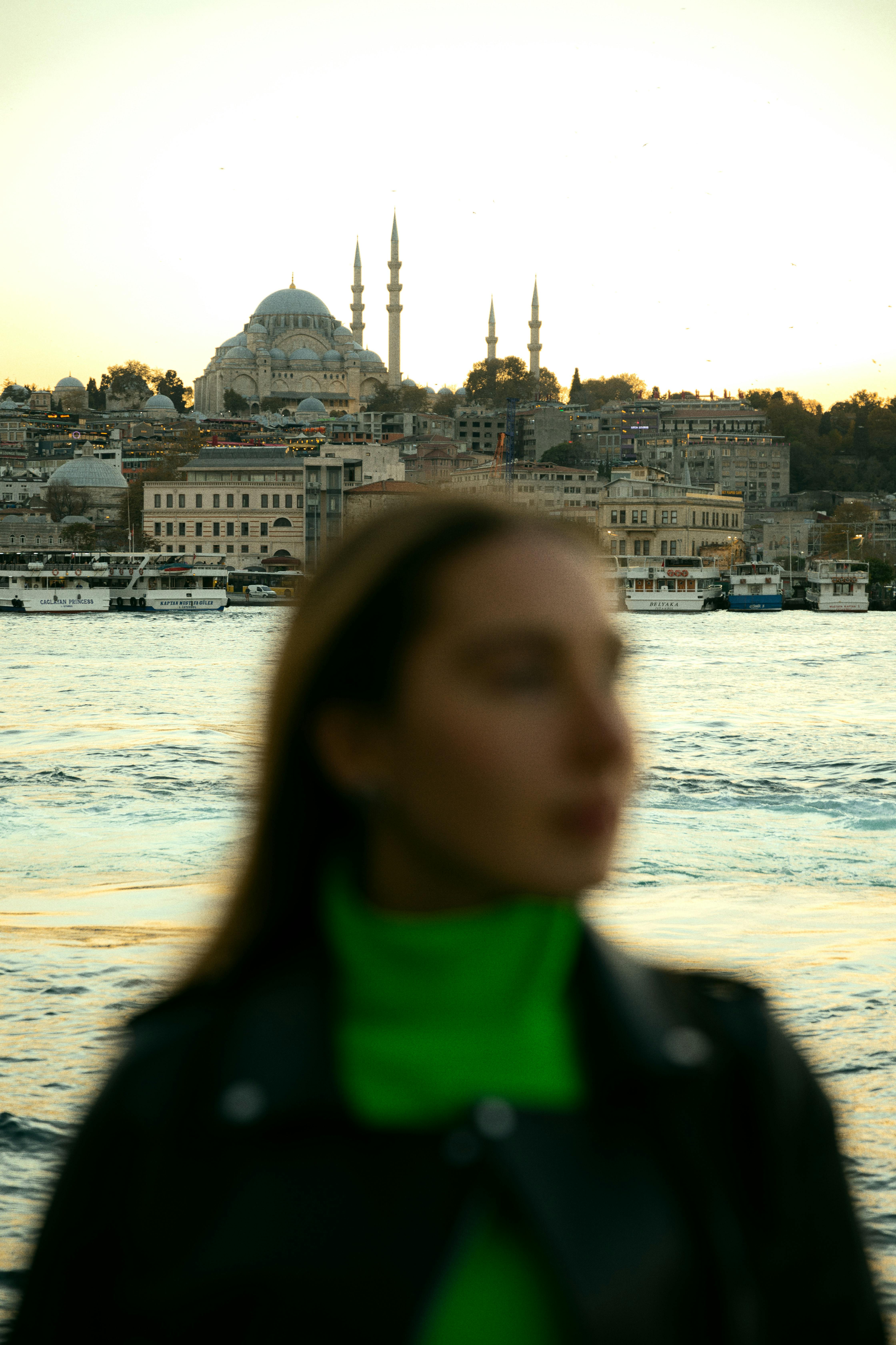 woman in front of river and mosque