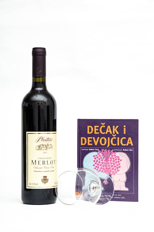 A bottle of wine and a book with a red cover