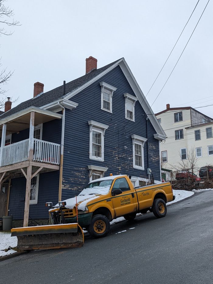 Pickup truck with a snow plow in front of houses