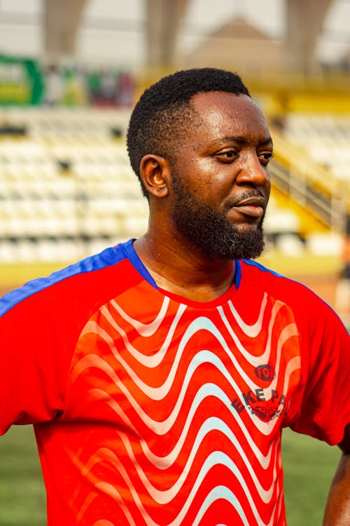 Free A man in a red and blue shirt standing on a soccer field Stock Photo