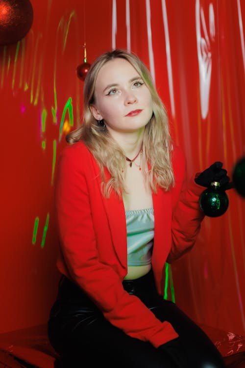 Model in a Red Blazer over a Silver Crop Top and Leatherette Pants Holding a Christmas Bauble