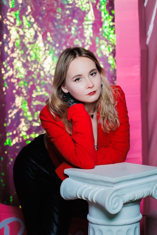 A woman in a red jacket posing on a pedestal