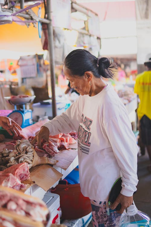 A woman is looking at some meat at a market