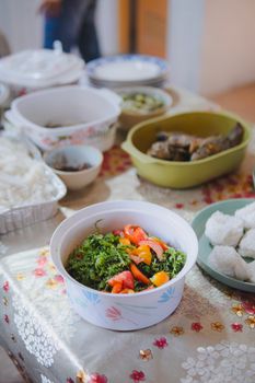 A vibrant salad and various dishes arranged on a decorated table indoors.