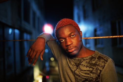 Free Stylish young man with red hair poses under city lights, capturing the essence of urban nightlife. Stock Photo