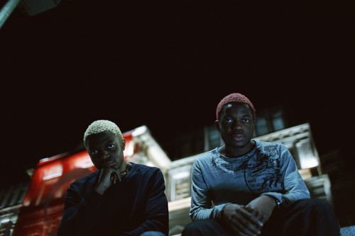 Free Two young men with styled hair in a dimly lit urban setting at night. Stock Photo