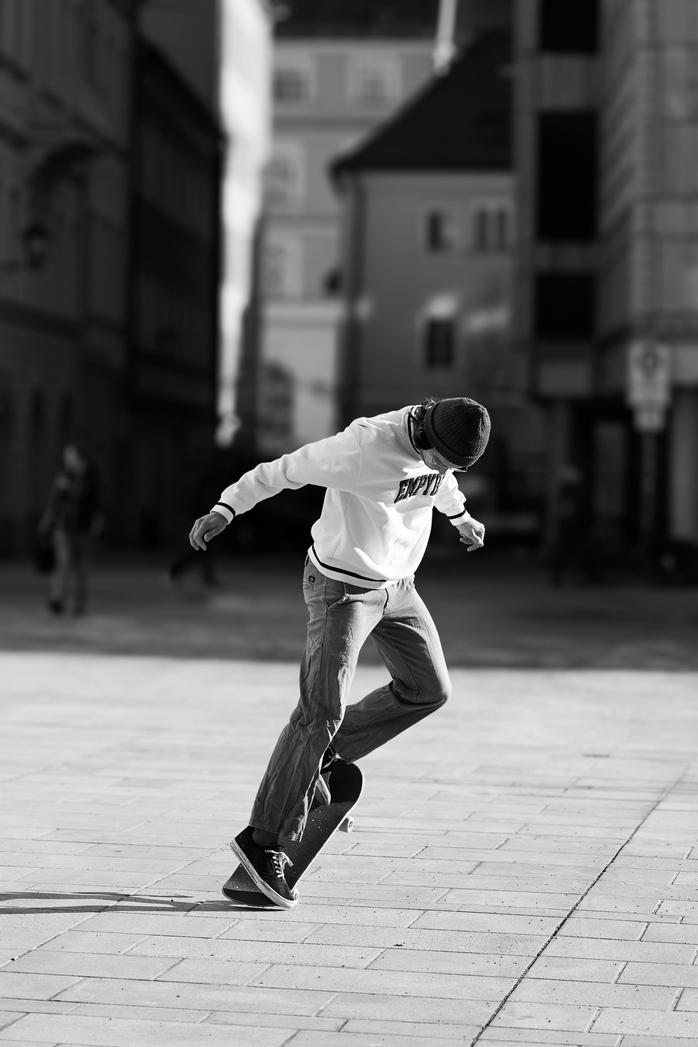 Young skateboarder performing a trick in a city square, captured in black and white for an urban vibe.