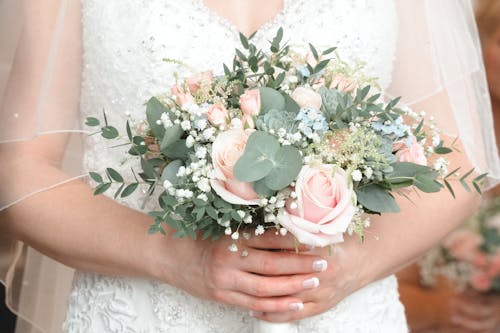 Closeup of a Bride Holding a Bouquet with Pastel Pink Roses and Green Leaves