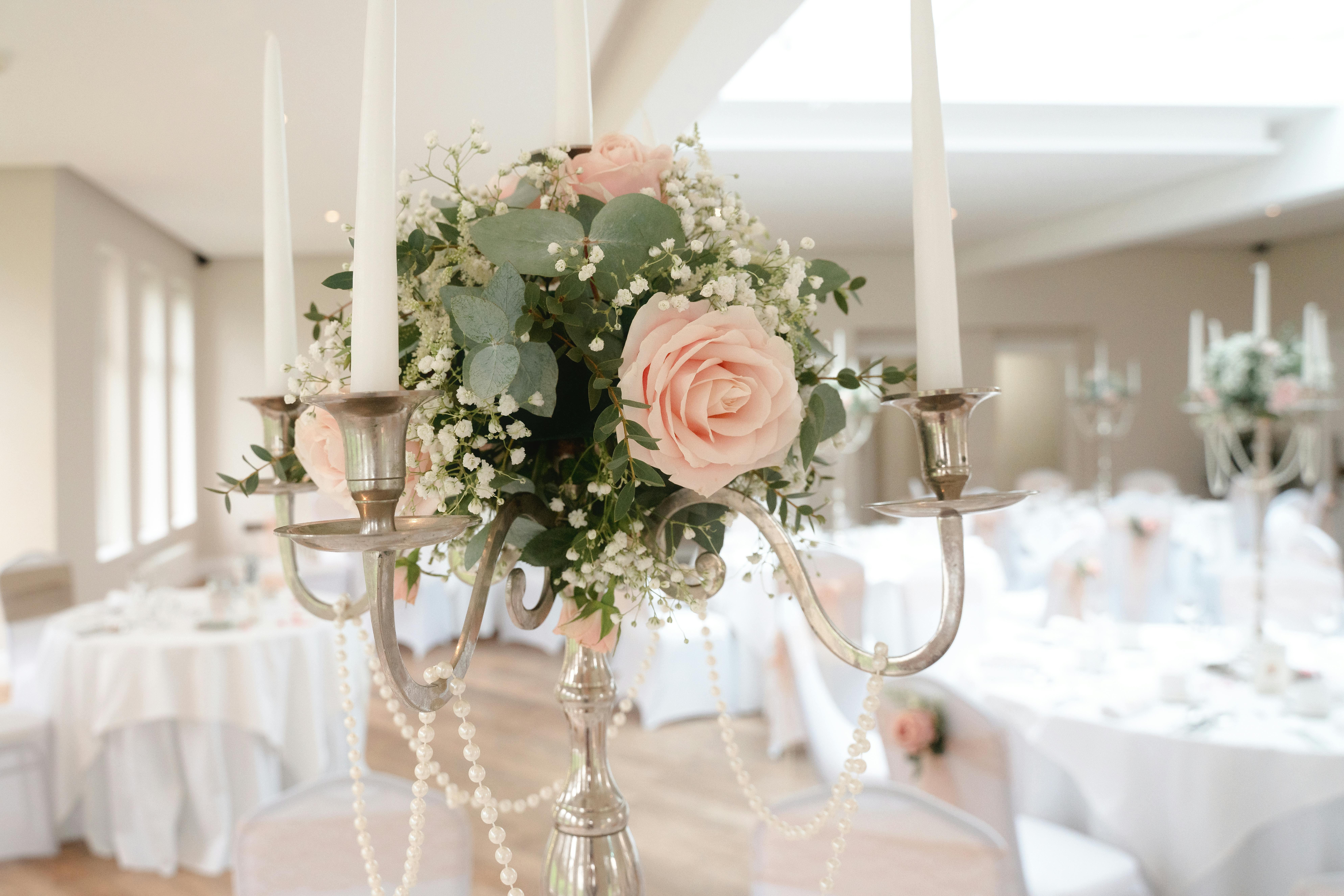 Beautiful wedding table centerpiece with pink roses and candles in a bright indoor setting.