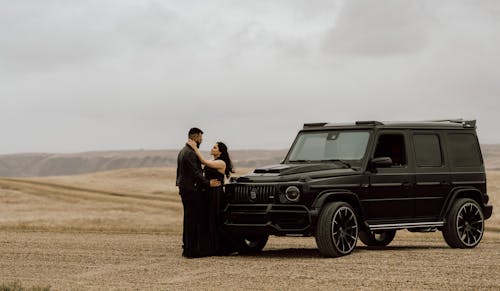 A couple standing in front of a black mercedes
