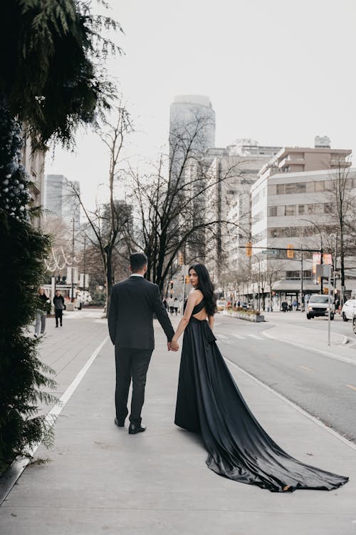 A bride and groom walking down the street in black gowns