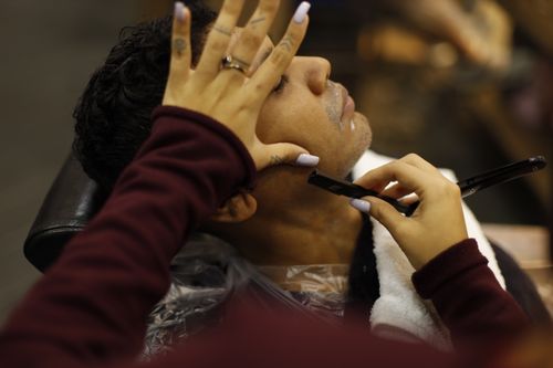Free A man enjoys a professional shave at a barbershop, showcasing relaxation and grooming. Stock Photo