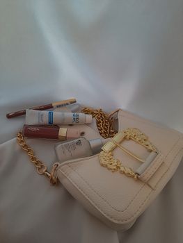 Stylish flat lay of a cream purse with cosmetics on a white background. Perfect for fashion blogs.