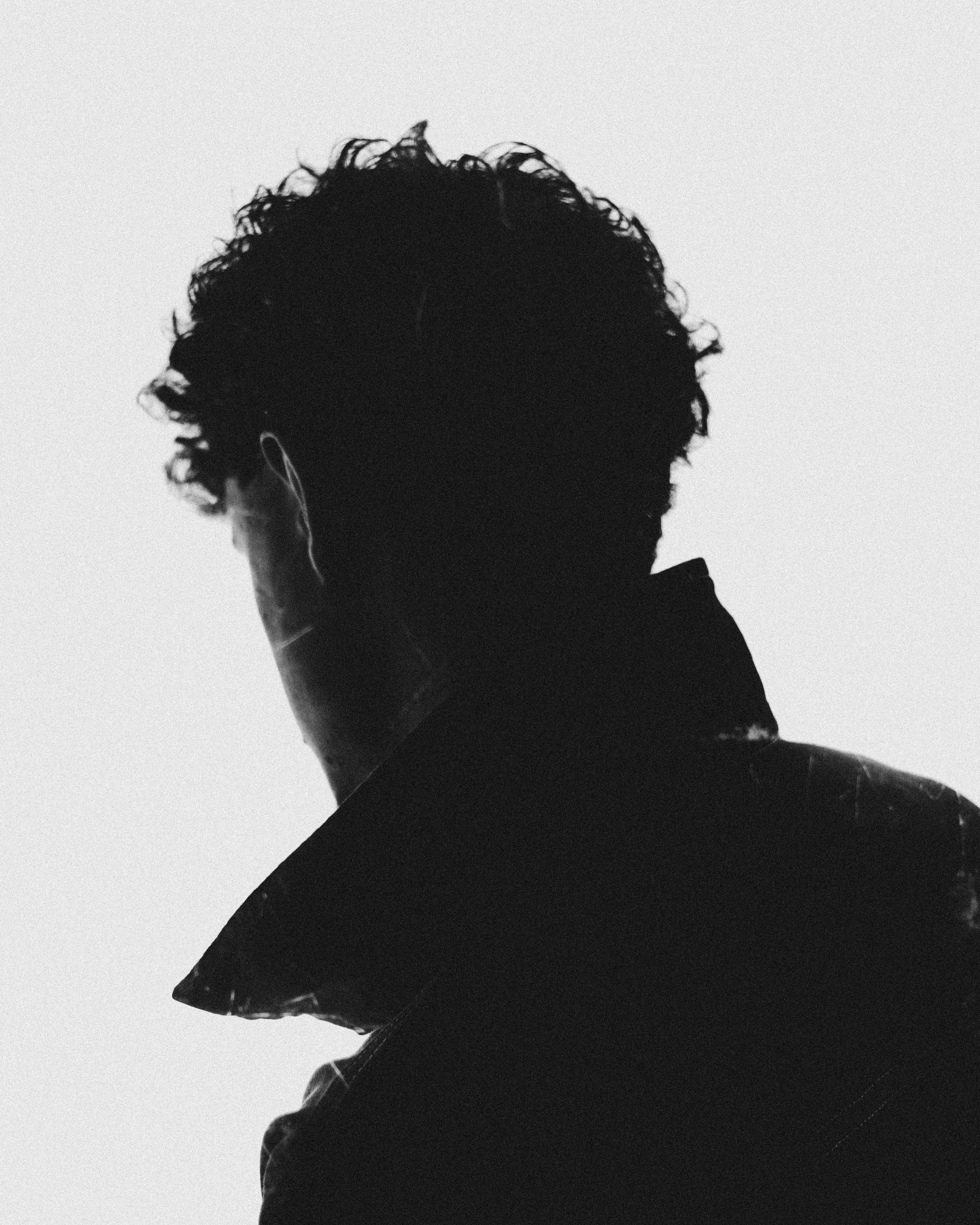 Black and white silhouette of a man in a stand collar taken in a studio setting.