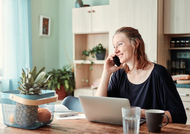 Woman Talking On Phone At Dining Table