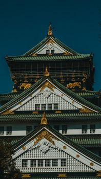 Vertical shot of the ornate facade of Osaka Castle, showcasing traditional Japanese architecture.