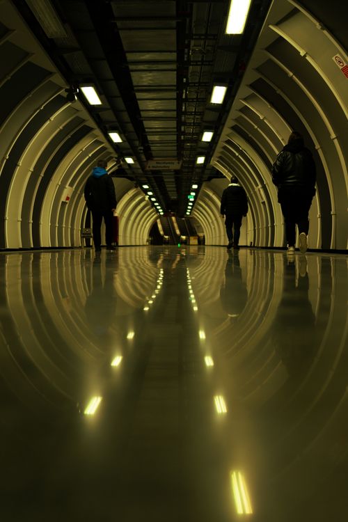 Free People walking in a well-lit urban tunnel in İstanbul with reflective flooring, creating an intriguing urban scene. Stock Photo