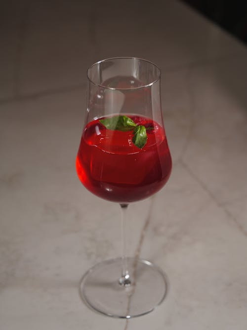 A glass of red wine with a garnish on top