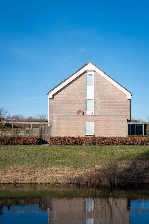 A house is sitting on a grassy field next to a body of water