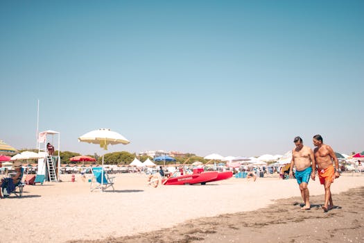 A sunny day at Venedik beach with two men walking and colorful umbrellas.