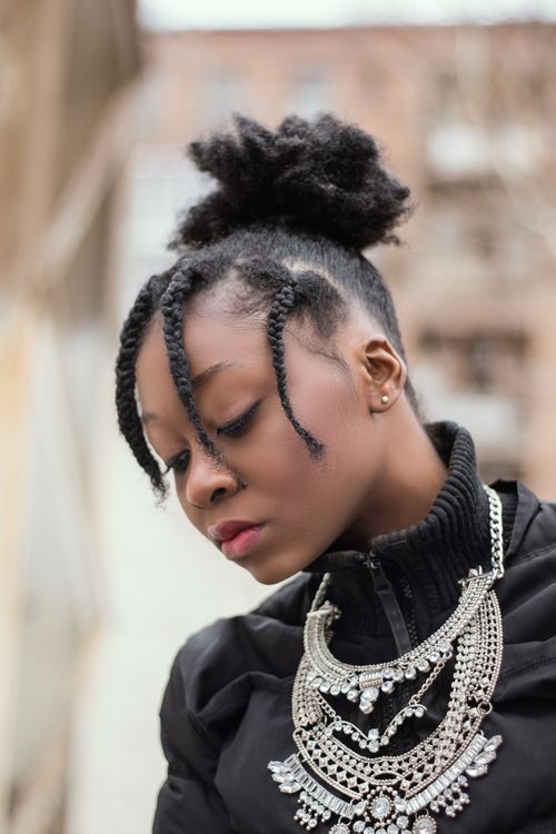 Free Close-up portrait of a woman in braids and silver necklace focusing downward. Stylish and elegant. Stock Photo