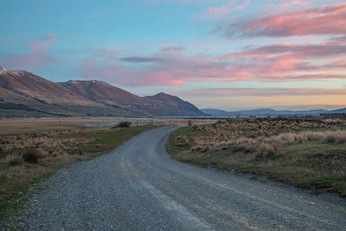 A dirt road with mountains in the background