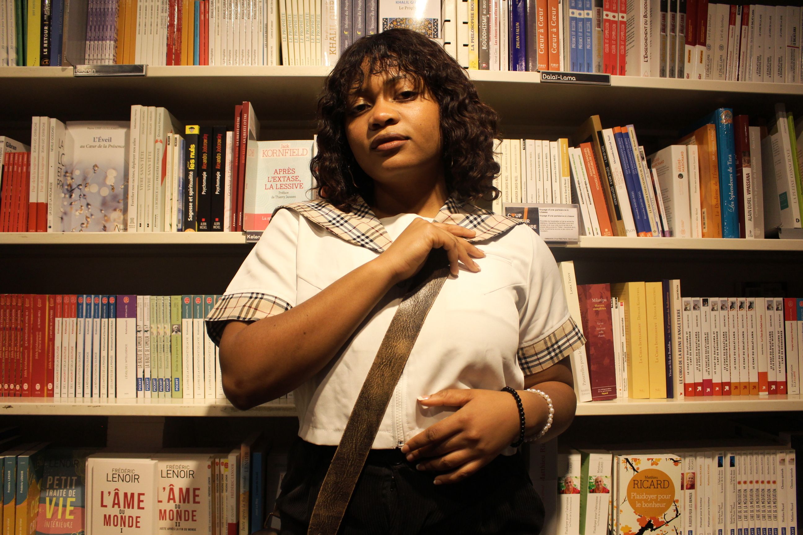 Portrait of a fashionable woman standing in a library surrounded by books.