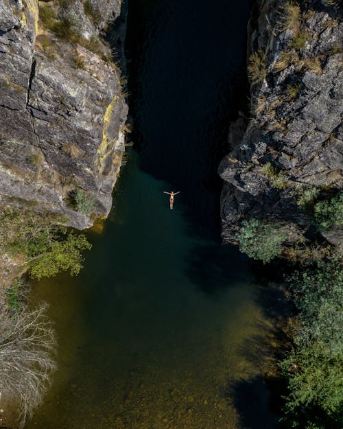 A person is swimming in a river near a cliff