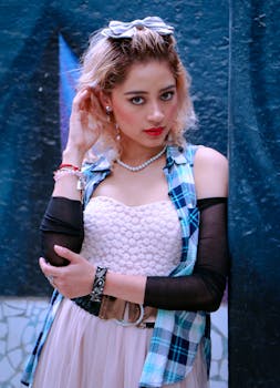 A fashionable woman poses confidently in a stylish layered outfit against a dark backdrop.