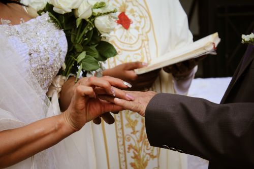 Free Close-up of a bride and groom exchanging rings during a wedding ceremony with a priest. Stock Photo