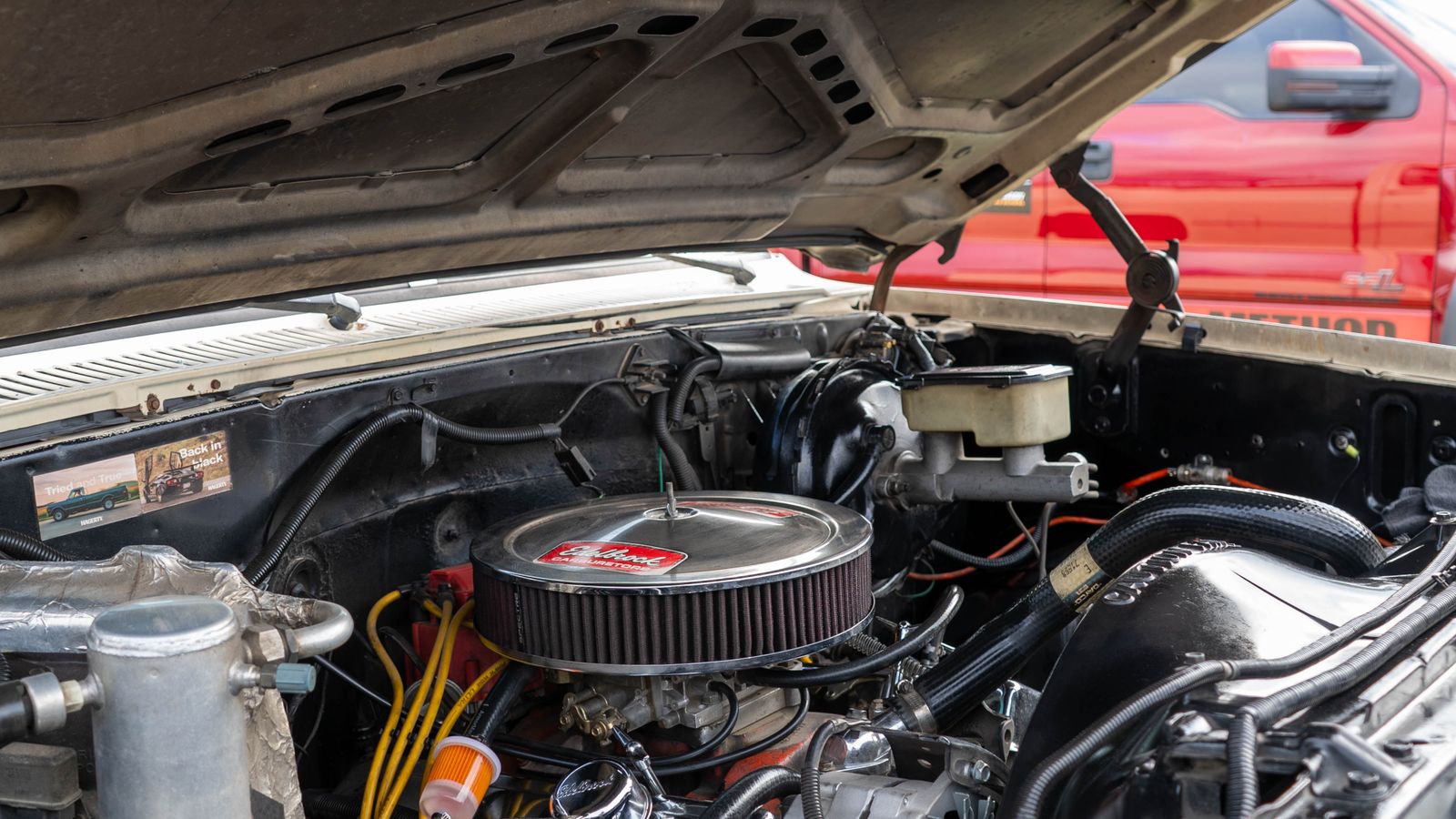 Mecânico inspecionando o compartimento do motor de um carro usado em busca de vazamento de combustível