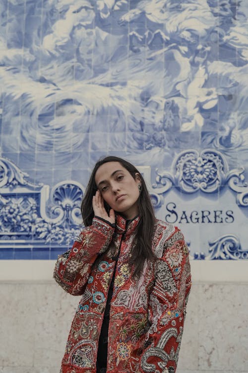 Young Woman in a Patterned Jacket Standing near a Wall with Art