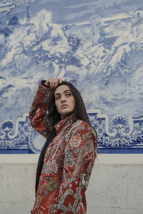 Young Woman in a Patterned Jacket Standing near a Wall with Art