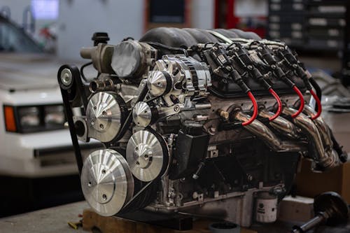 Close-up of an Engine and a Car in the Background in a Garage 