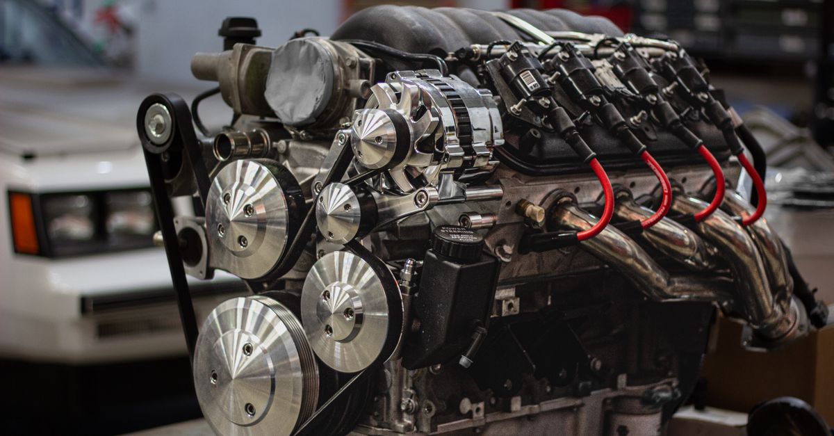 Detailed shot of a powerful car engine in a garage setting, highlighting mechanical components.