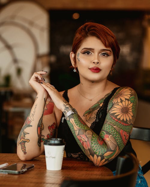 Woman with Tattoos and Short Hair Sitting by Table