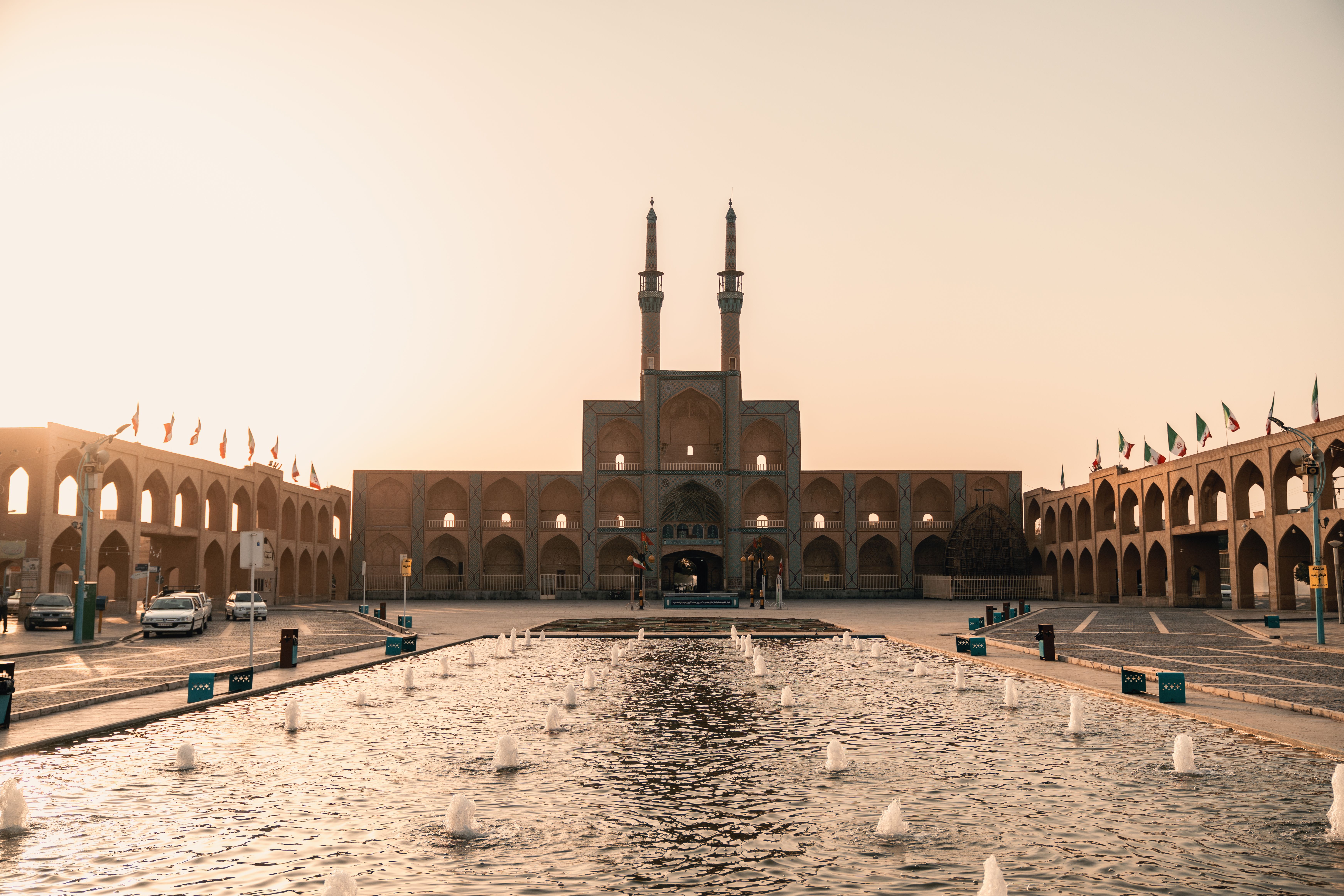 View of the Amir Chakhmaq Complex in Yazd, Iran, at dusk with a serene fountain reflecting architecture.