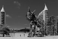 Monochrome image of Bordalo II's Iberian Lynx sculpture with modern Lisbon skyline.