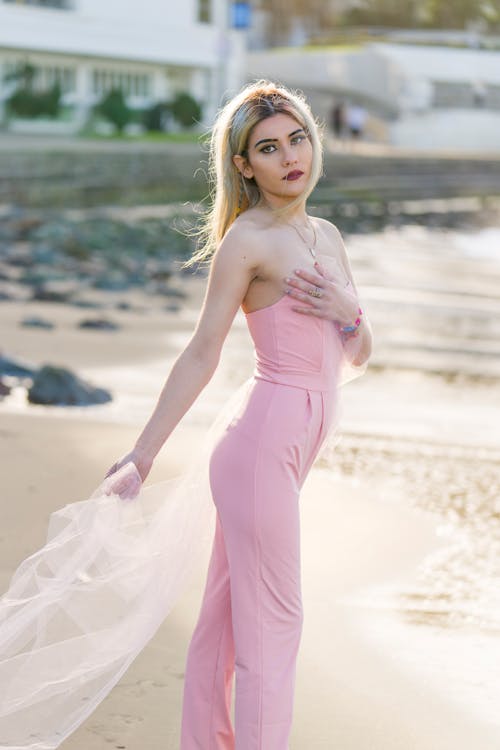 Blonde Woman in Pink Clothes and with Veil on Beach