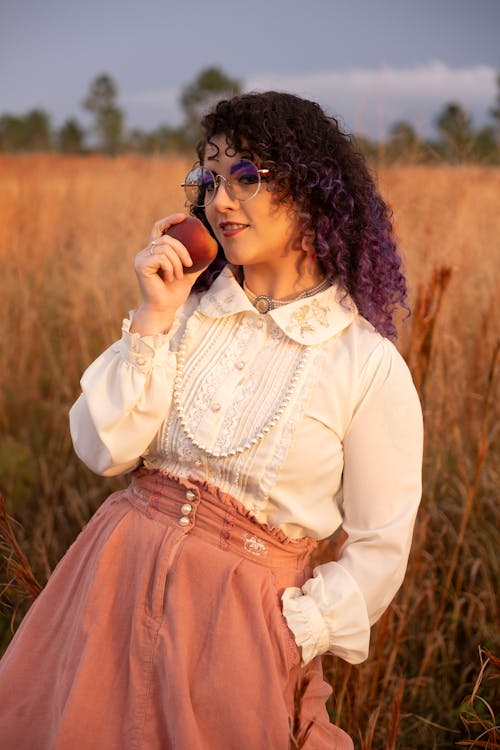 Woman Holding Peach in Meadow