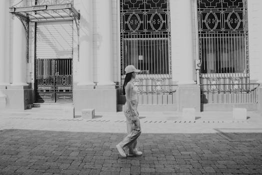 Black and white photo of a woman walking past ornate urban architecture.
